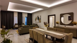 A modern living room with a sofa set, a dining table, and a large mirror. - Luxury 3 Bedroom apartment (Kinshasa)