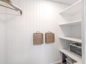 A white-paneled closet with two wicker baskets hanging on the wall and a shelving unit below. - "Varnava" - 300m from the sea by Interhome (Grenaa)