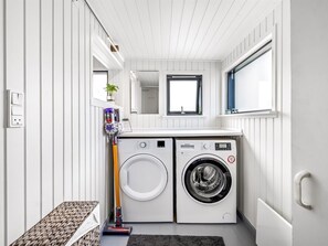 A compact laundry room with a washing machine, dryer, and a small seating area. - "Varnava" - 300m from the sea by Interhome (Grenaa)