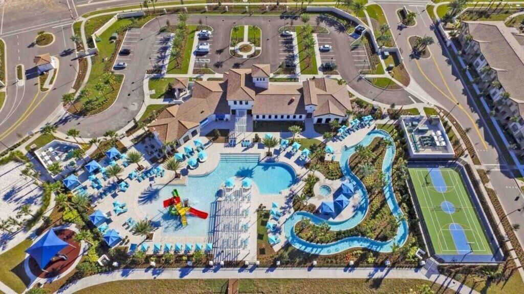 Luchtbeeld van een resort met een zwembad, waterglijbanen en een tennisbaan.