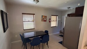 A kitchen with a dining table and chairs, a refrigerator, and a window with blinds. - Cozy 2-bedroom villa with Pool in sunny Miami (Miami)