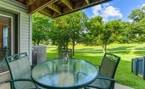 A covered patio with a round glass table and chairs, overlooking a well-manicured lawn and trees. - Birdie's Nest and 2BDR Condo (Branson)