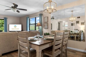 A dining area with a wooden table and chairs, a ceiling fan, and a chandelier. - Birdie's Nest and 2BDR Condo (Branson)