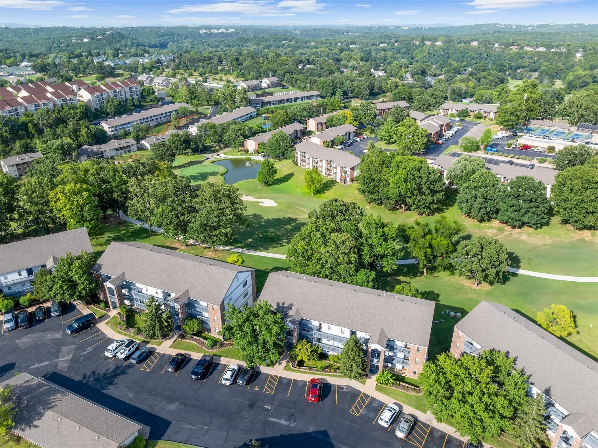 Vista aérea de una zona residencial con edificios de apartamentos, un campo de golf y un estacionamiento.