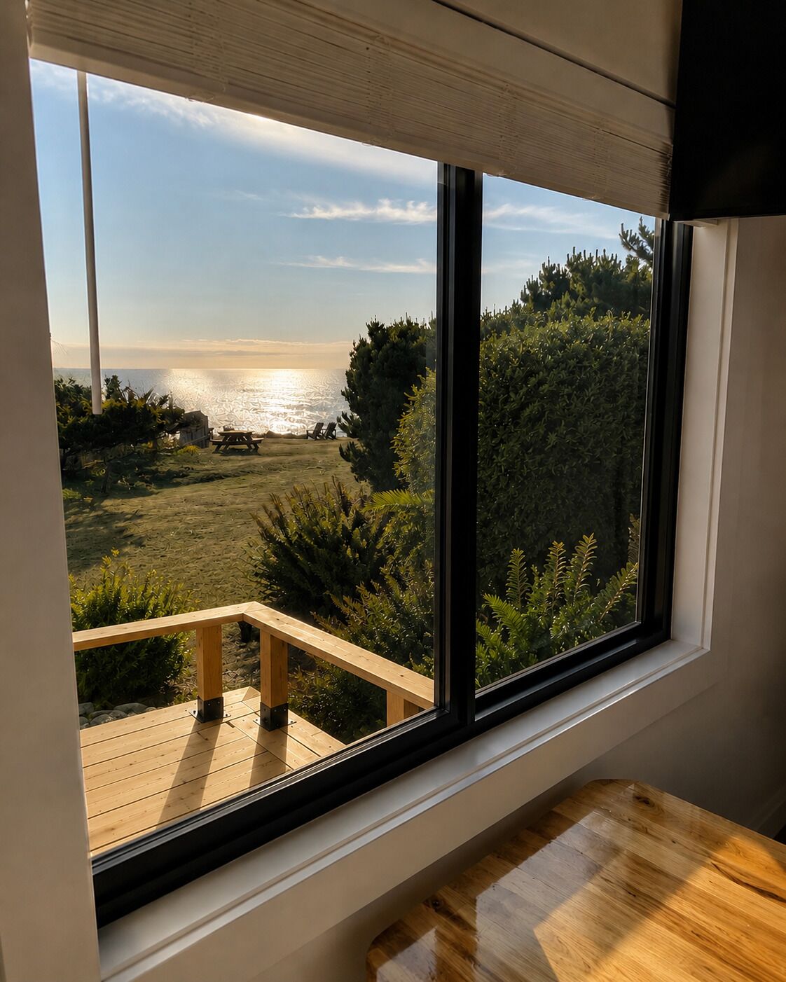 Une pièce dotée d ’une grande fenêtre donnant sur une terrasse et un paysage naturel.