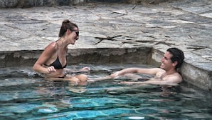 Two people in a stone-bottomed pool with clear water. - Eco Quechua  (Santa Teresa)