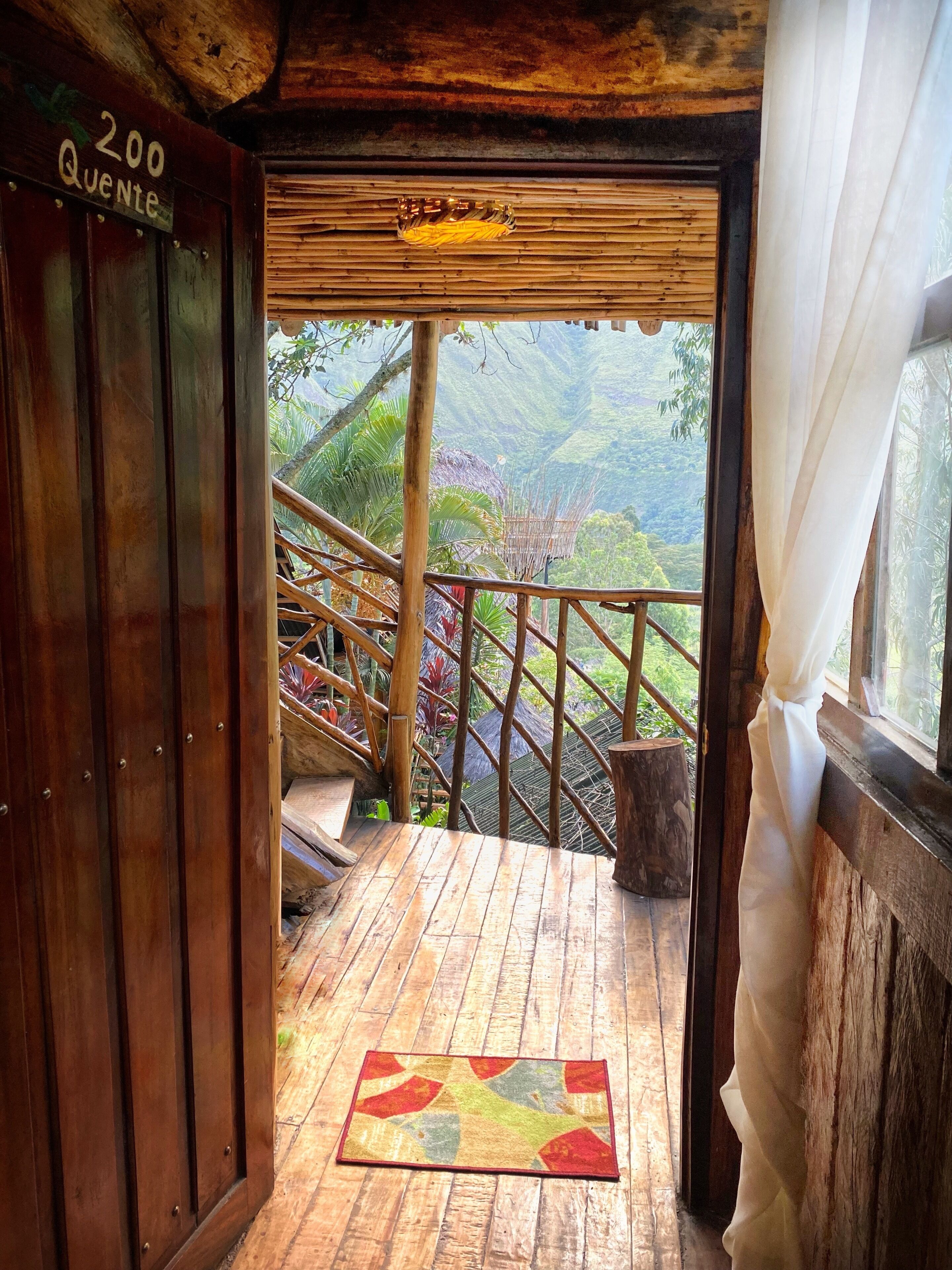 Uma escadaria de madeira leva a uma varanda com vista para uma paisagem montanhosa.