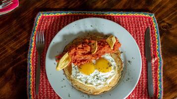 Een bord met eieren, tomaten en toast op een tafel met een kleurrijke placemat.