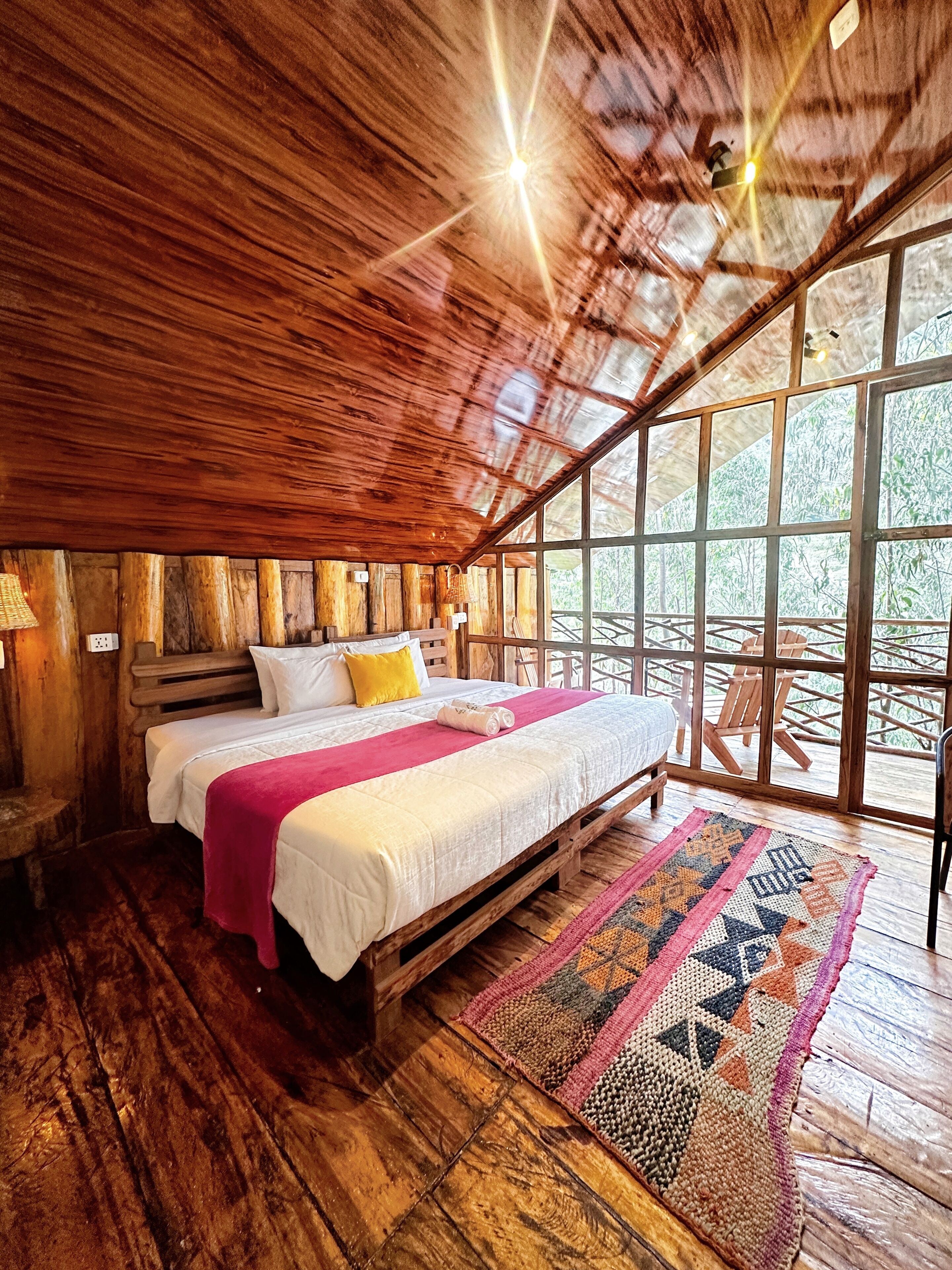 A wooden interior with a bed, a window, and a ceiling light.