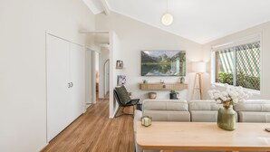 Una sala de estar moderna con un sofá, una mesa de madera y un cuadro de un paisaje montañoso.