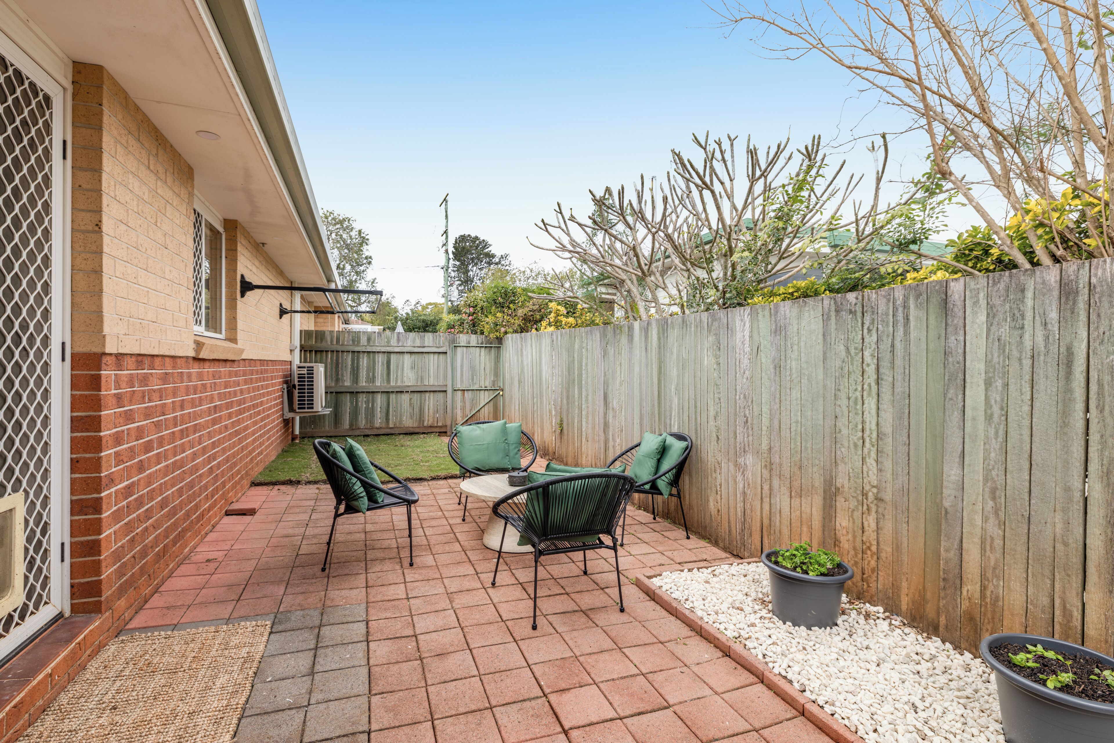 A patio with a brick floor, outdoor furniture, and a wooden fence.