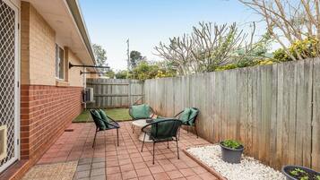 A patio with a brick floor, outdoor furniture, and a wooden fence.