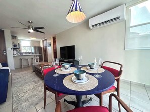 A dining area with a round table, chairs, and a television in the background. - Trade Winds | Family Vacation PH | Near Ferry (Ceiba)