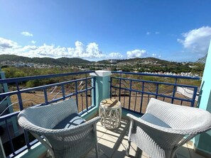 A balcony with wicker furniture and a view of a hilly landscape. - Trade Winds | Family Vacation PH | Near Ferry (Ceiba)