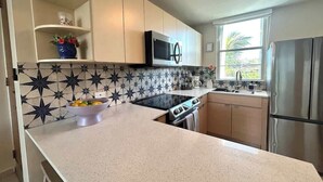 A kitchen with a microwave, stove, sink, and stainless steel refrigerator. - Trade Winds | Family Vacation PH | Near Ferry (Ceiba)