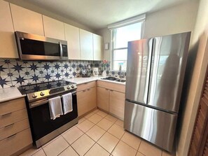 A kitchen with a microwave, oven, and refrigerator. - Trade Winds | Family Vacation PH | Near Ferry (Ceiba)