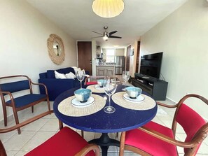 A dining area with a round table, chairs, and a television in the background. - Trade Winds | Family Vacation PH | Near Ferry (Ceiba)