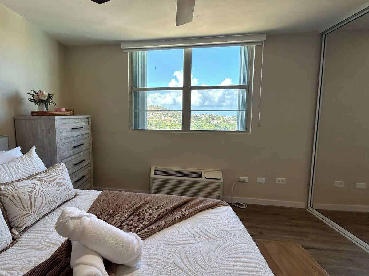 Een slaapkamer met een bed, een dressoir, een raam met uitzicht en een airconditioning.