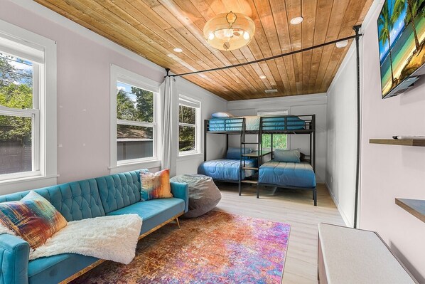 A modern room with a blue sofa, bunk beds, and a large window.