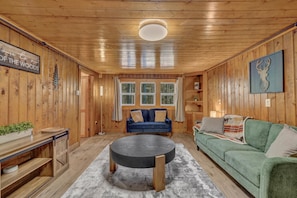 A cozy cabin interior with a round table, a blue sofa, and a green couch. - Rancho McCrea Retreat is your perfect Yellowstone Vacation destination! Dogs ok (Island Park)