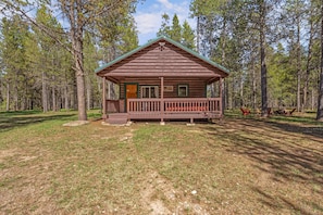 A wooden cabin with a porch, surrounded by a forest. - Rancho McCrea Retreat is your perfect Yellowstone Vacation destination! Dogs ok (Island Park)