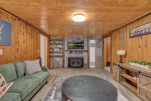 A cozy cabin interior with a stone fireplace, a green sofa, and a round table. - Rancho McCrea Retreat is your perfect Yellowstone Vacation destination! Dogs ok (Island Park)