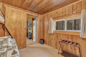 Ein Zimmer mit Holzboden, einem Bett, einem Fenster mit Vorhängen, einem Heizkörper und einer Heizkörperabdeckung.