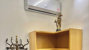 Habitación de esquina con un armario de madera, un perchero y un candelabro decorativo.