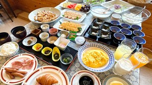 A breakfast buffet with various dishes, including eggs, meats, pastries, and beverages.