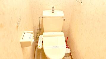A small, narrow bathroom with a toilet, a bidet, and a hand dryer.