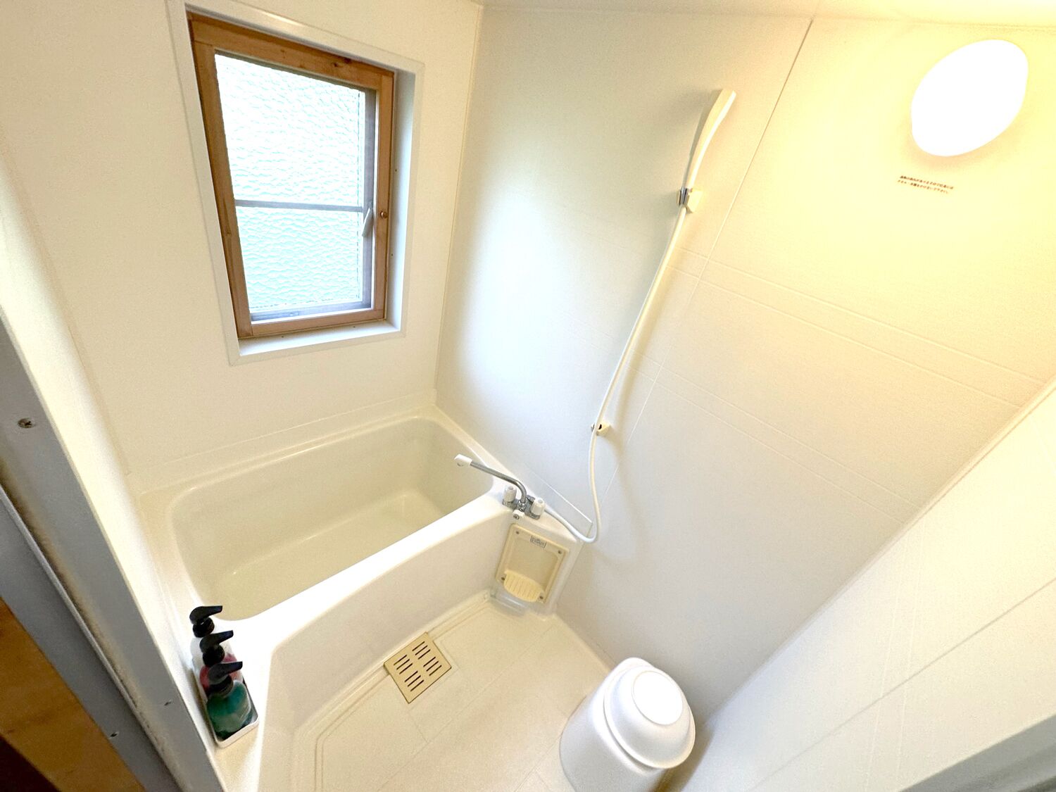 A small bathroom with a bathtub, a window, and a shower.