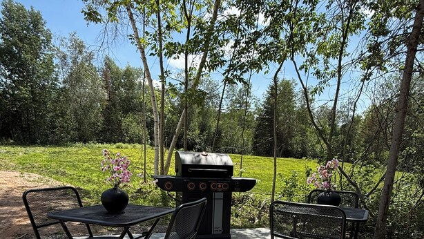 An outdoor patio with a grill, two chairs, and a table. - Sakura Valley Studio Suite #7 / Private Entrance in beautiful Annapolis Valley (North Alton)