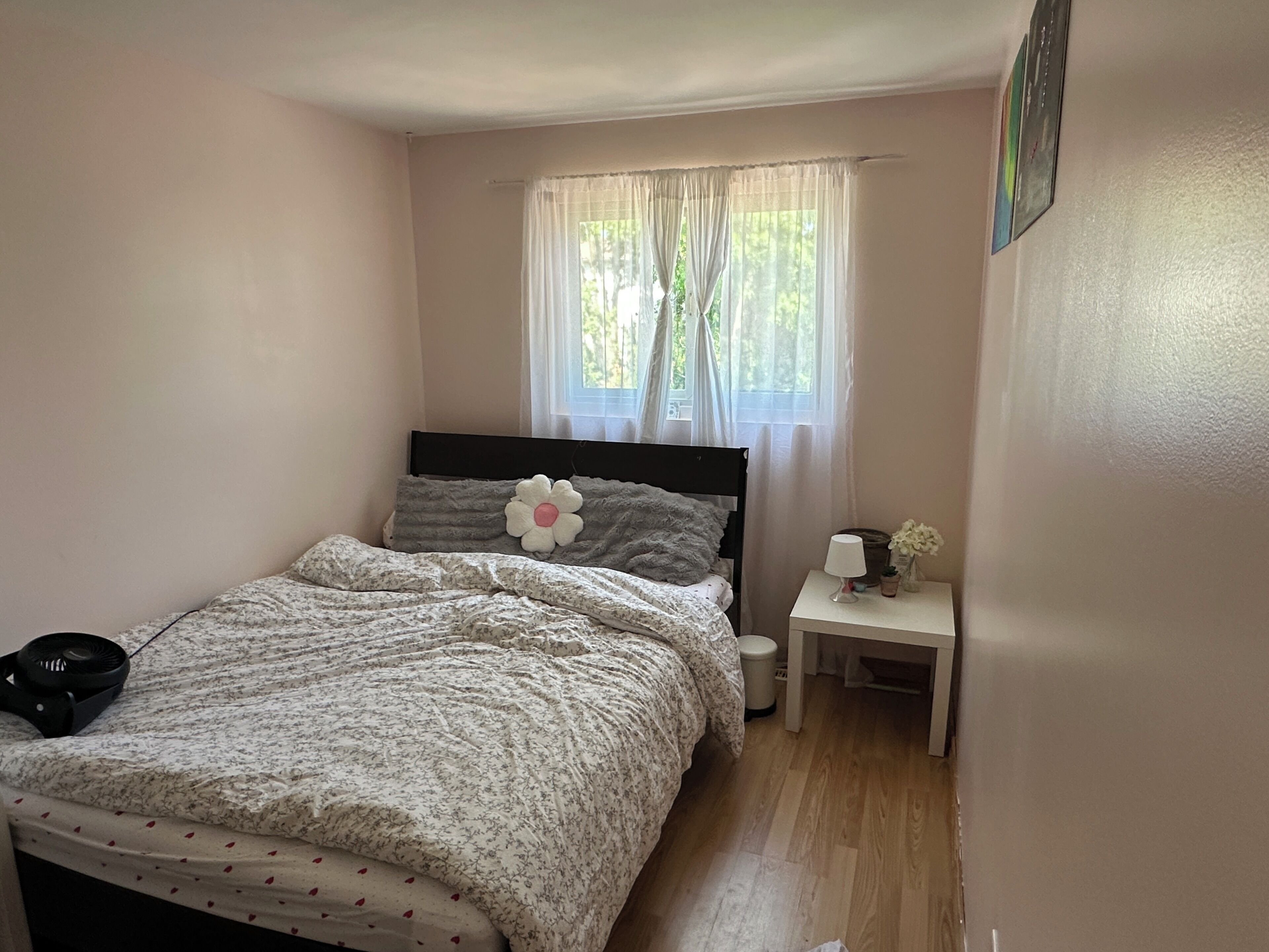 A bedroom with a bed, a bedside table, a lamp, and a window with curtains.