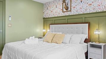 A hotel room with a large bed, two bedside tables, and a floral wallpaper design.