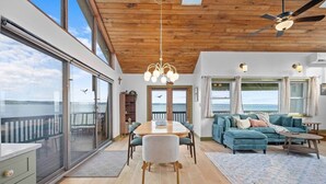 A spacious living area with a wooden ceiling, a dining table, and a sofa. - Long Point Lake House - Phil's Place (Ledyard)
