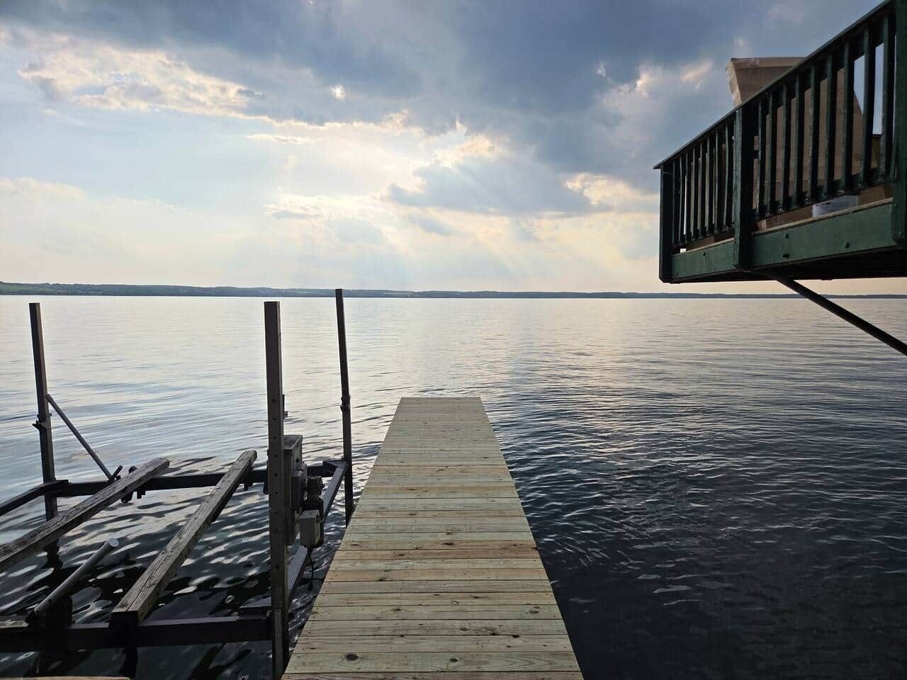 A wooden dock extending into calm water with a cloudy sky above.