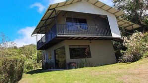 A two-story house with a balcony on the upper floor, surrounded by greenery. - Cecropia Paradise Monteverde (Santa Elena, Monteverde)