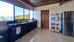 A kitchen with a gas stove, a microwave, and a stainless steel refrigerator. - Cecropia Paradise Monteverde (Santa Elena, Monteverde)