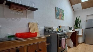 Een keuken met een gasfornuis, oven en een houten kast met lades.