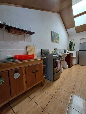 Una cocina con estufa a gas, horno y un mueble de madera con cajones.