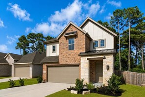 A residential building with a brick facade, a stone entrance, and a garage. - Luxury 4BR 3BA - Peaceful Forest Retreat (Willis)