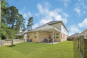 A two-story house with a covered patio, a fenced backyard, and a wooden fence. - Luxury 4BR 3.5BA - Peaceful Forest Retreat (Willis)