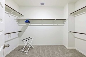 A compact, white-walled closet with multiple shelves and a folding chair. - Luxury 4BR 3.5BA - Peaceful Forest Retreat (Willis)