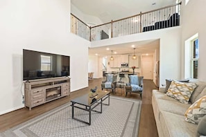 A spacious living area with a television, sofa, and coffee table. - Luxury 4BR 3.5BA - Peaceful Forest Retreat (Willis)