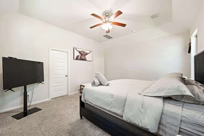 A bedroom with a bed, a television, a ceiling fan, and a door. - Luxury 4BR 3.5BA - Peaceful Forest Retreat (Willis)
