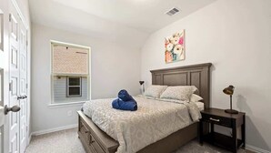 Un dormitorio con cama, mesita de noche, ventana con persianas y puerta.
