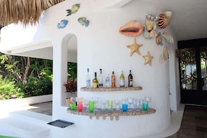 Eine Bar mit Flaschen- und Gläserregalen, umgeben von dekorativen Muscheln und Seesternen.