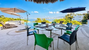 An outdoor dining area with a view of the sea, surrounded by greenery and equipped with umbrellas and chairs. - 7BR Villa with Private Pool & Spectacular Views (Acapulco de Juárez)