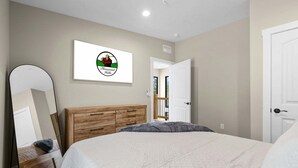 Un dormitorio con cama, cómoda de madera, espejo y puerta.