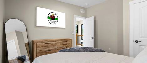 A bedroom with a bed, a wooden dresser, a mirror, and a door.